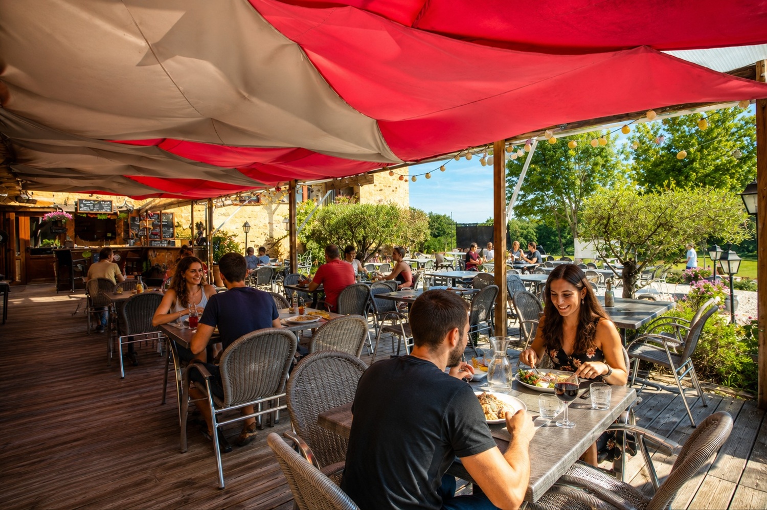 Des vacanciers réunis sur la terrasse ombragée du camping