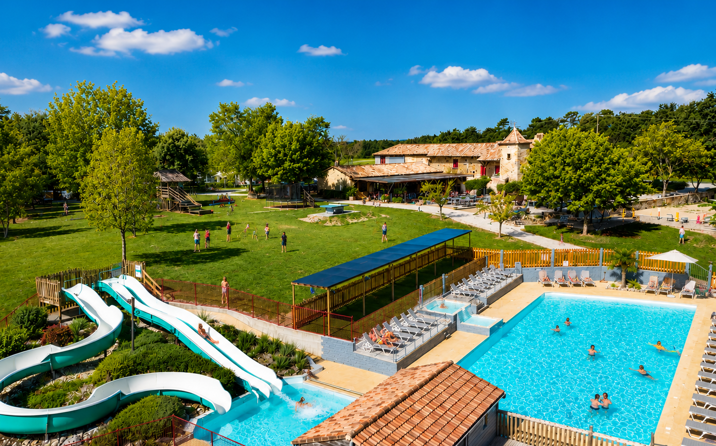 Vue aérienne naturelle du Camping Las Patrasses en Dordogne : piscine chauffée à toboggans, bâtisse en pierre et grands espaces familiaux